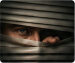 Person peeking through horizontal window blinds, only their eyes visible outside the slats.